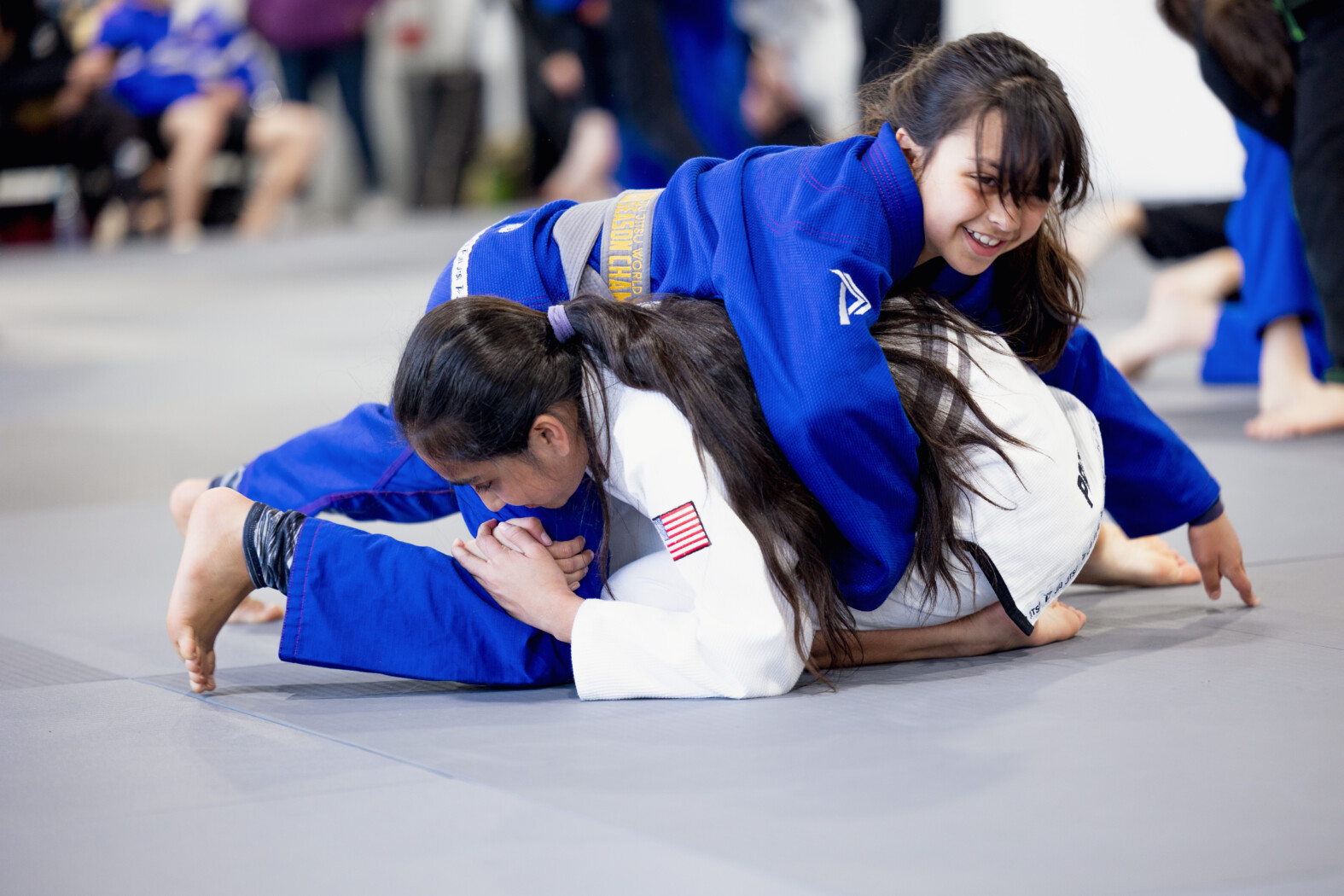 Two young ladies smiling while training Brazilian Jiu Jitsu at Progresso Jiu Jitsu