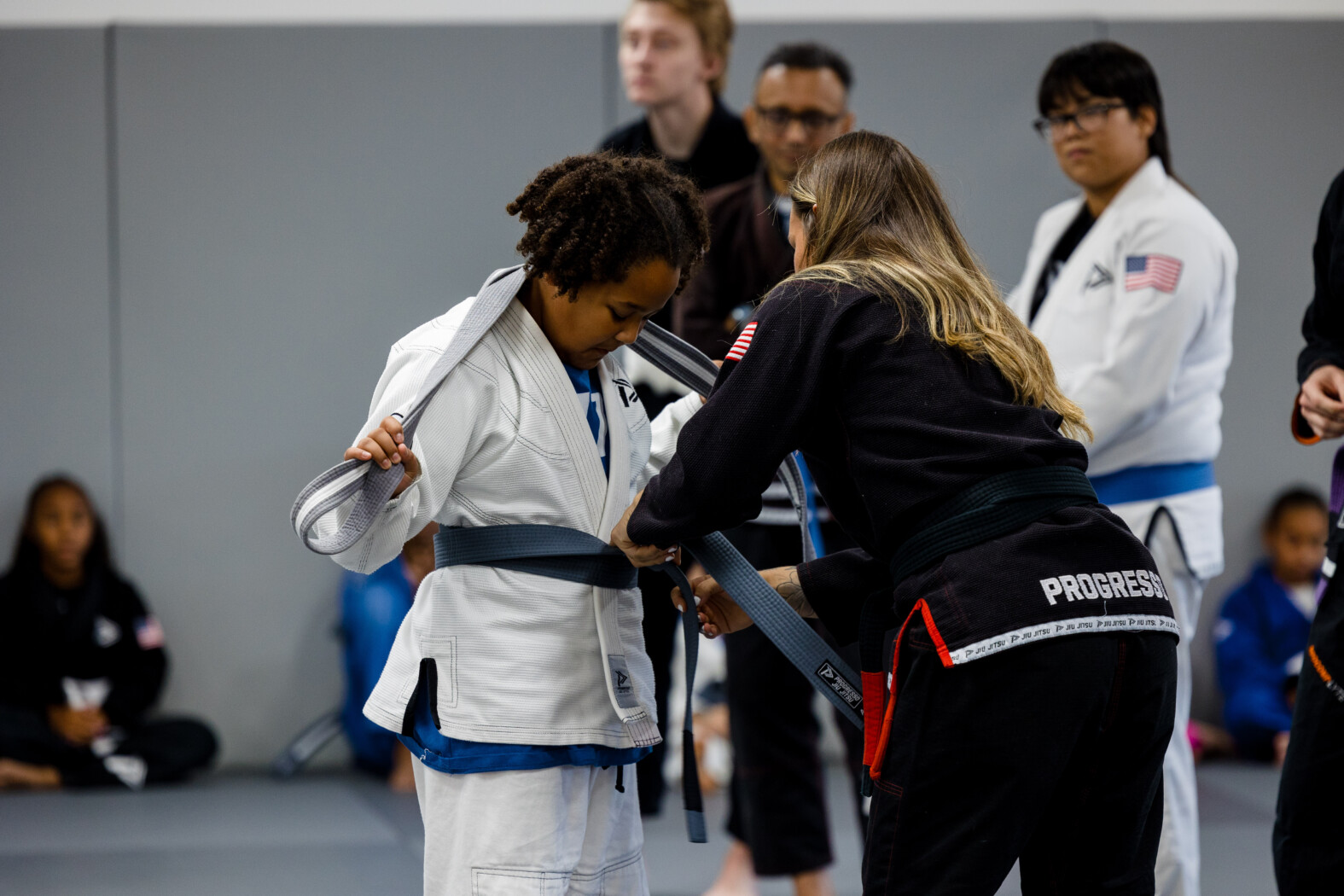 Instructor places a new belt on a young Jiu Jitsu student