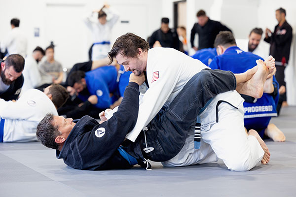 Image of multiple jiu-jitsu athletes grappling on a mat